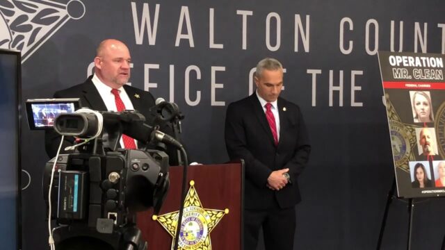 Sheriff Michael Adkinson standing at a podium with a sheriff star emblem on the front addressing members of the media