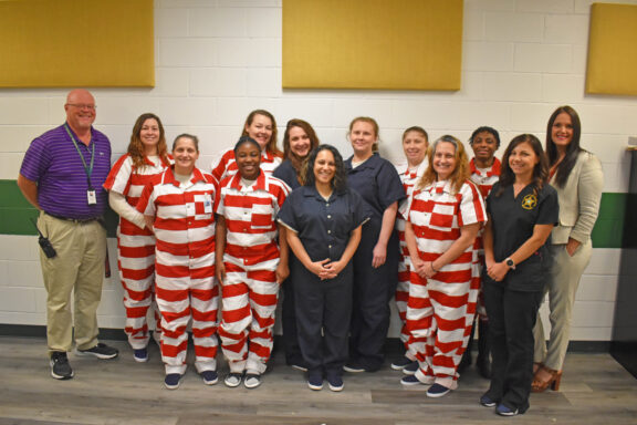 Female inmates in dark blue and red and white striped uniforms